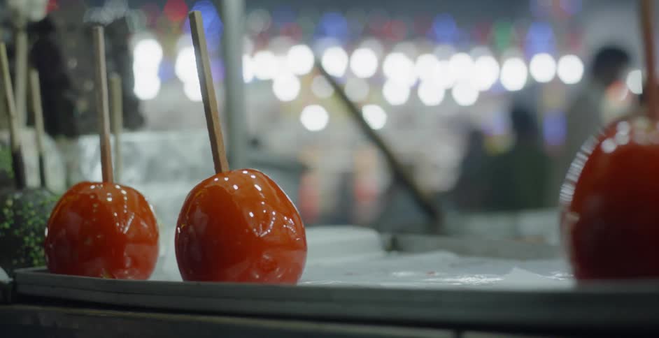 Candy apples sit on the table of a busy festival