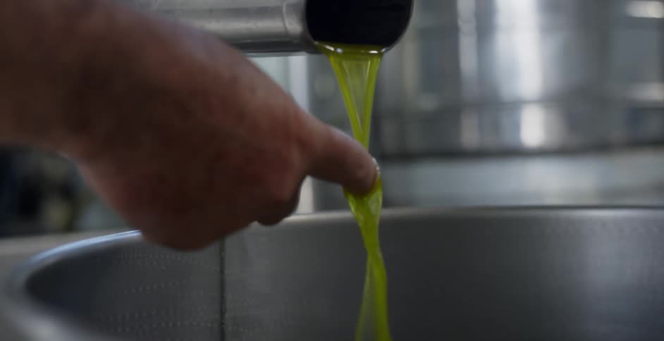 A man sticks his finger in freshly pressed olive oil