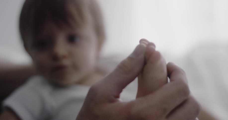 A man is playing with a babies foot and pretending to bite them