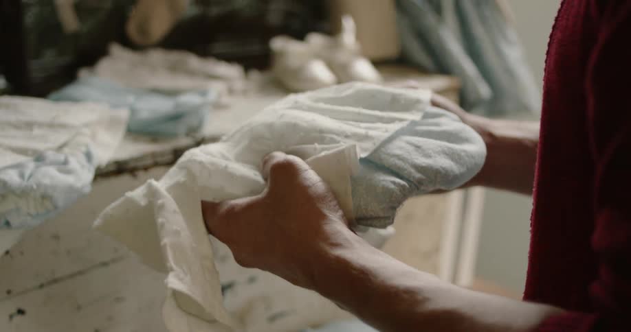 Man holds and examines baby clothes