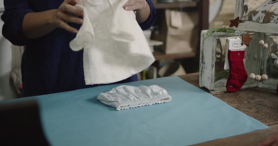 A woman is folding baby clothes
