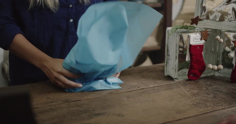 Woman wrapping an item with tissue paper and placing it in a gift bag