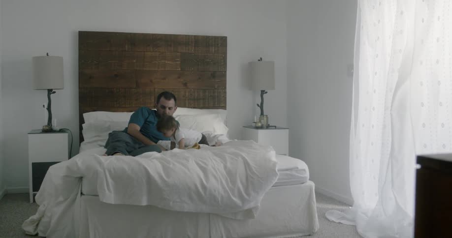 A man and a baby are playing in the bed
