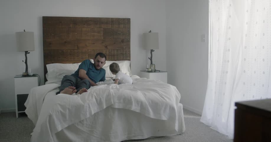 A man and a baby are playing on the bed