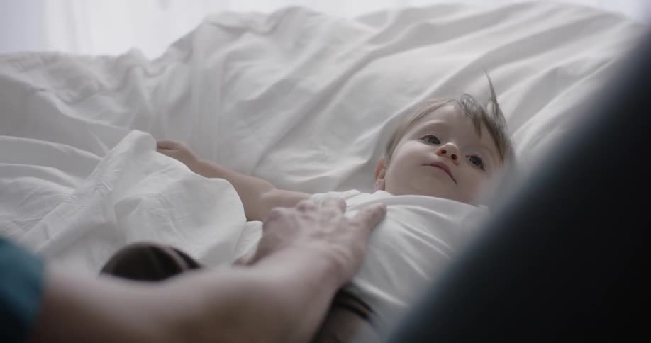 A man is rubbing the chest of a baby lying on a bed