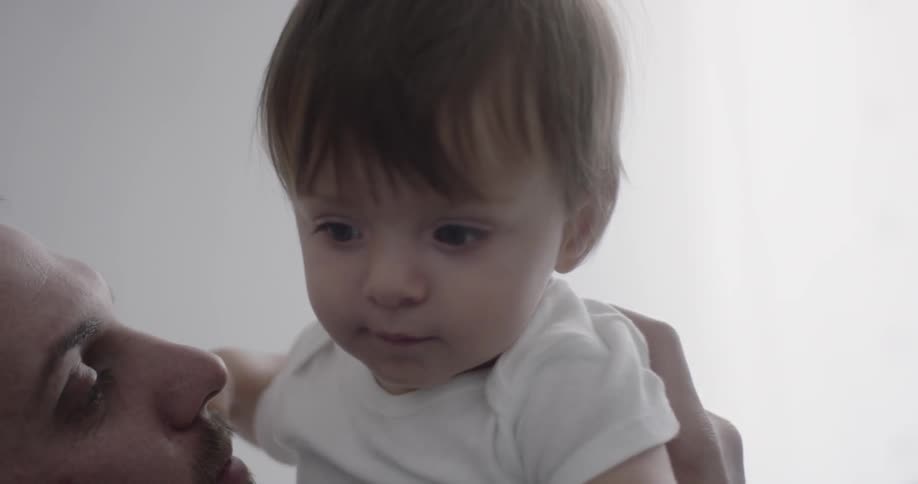 A dad is playing with his baby in bed