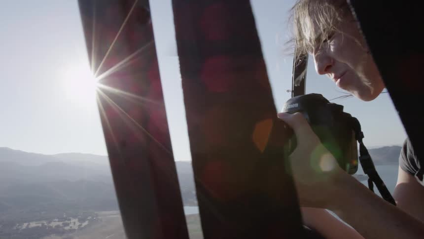 Person taking photographs from an open helicopter on a sunny day