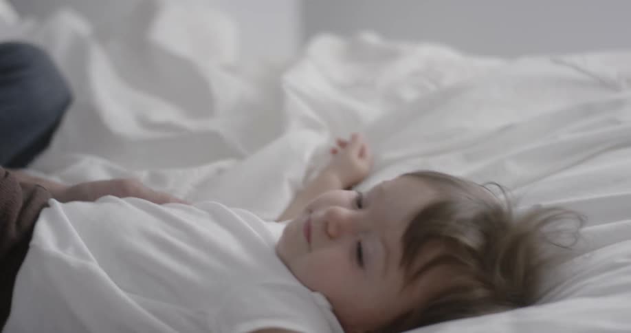 Man plays with a baby in bed
