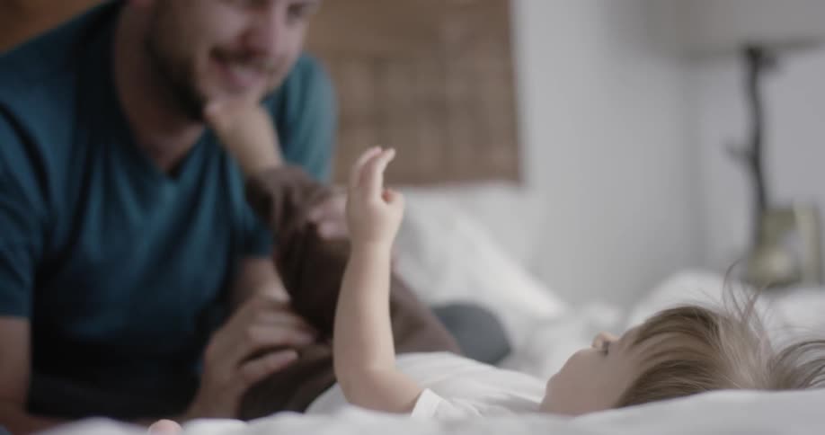 Man plays with a baby in bed