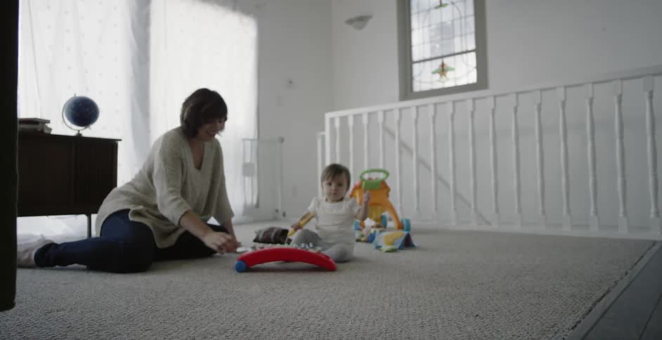 A baby and mother are playing together on the floor