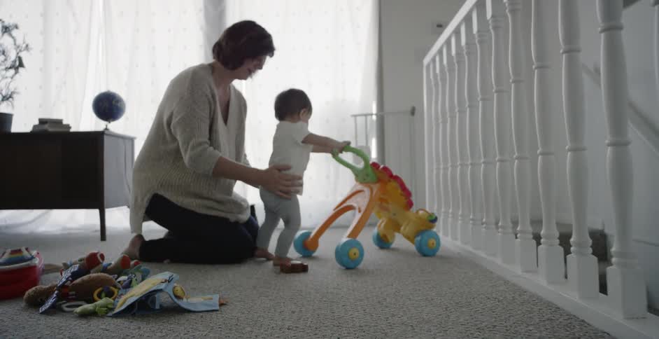 Woman places baby next to a toy stroller