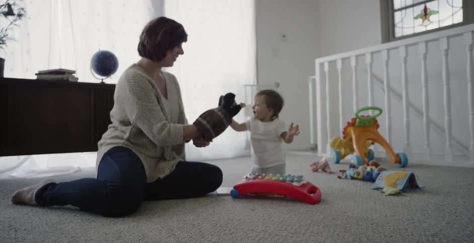 A mother and baby are playing on the floor together