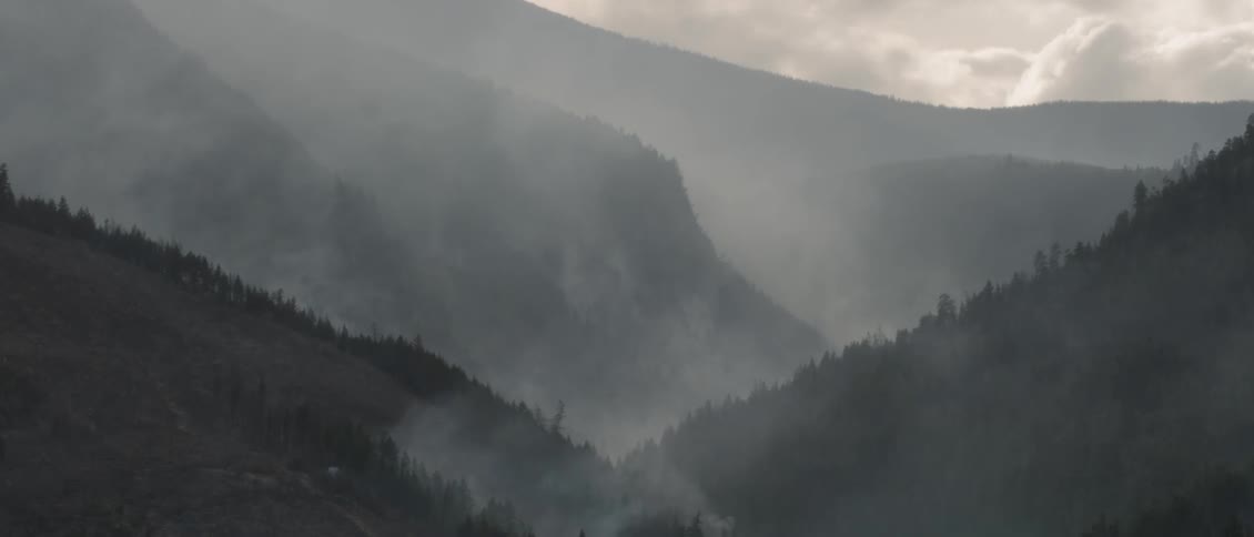 Smoke floats over tree covered hills