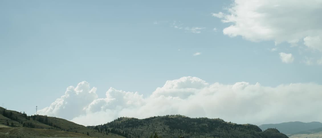 White clouds pass above the hills