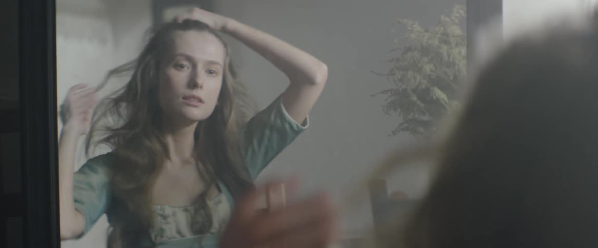 A woman brushes her hair in the mirror