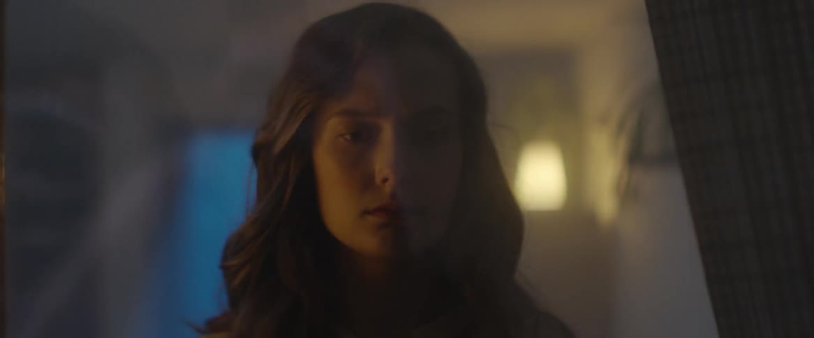 A light shines behind a woman who is standing and staring