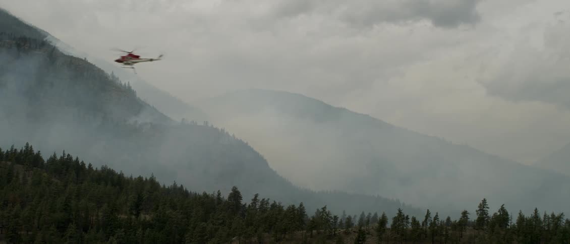 Helicopter flies low over smoky hills