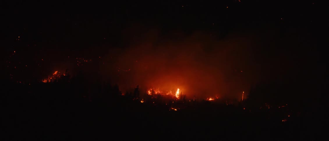Fires burn under a dark sky