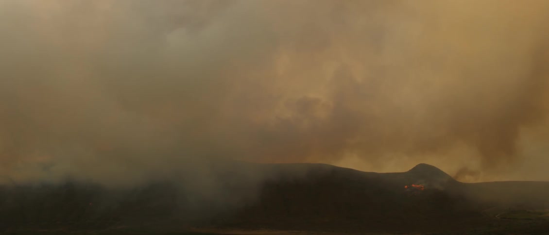 Smoke pours from a smoldering fire