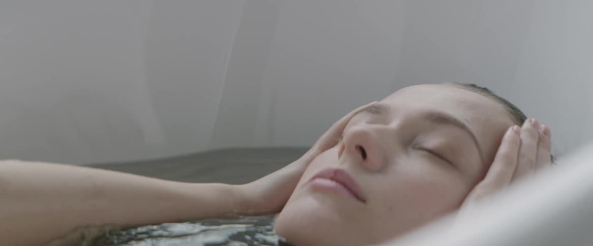 A woman lays back washing in the tub