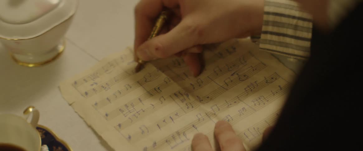 A composer writes on a music sheet