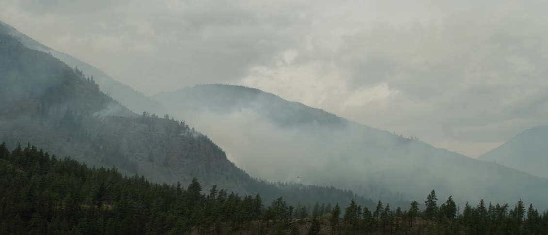 Clouds lingering in a valley between some mountains on an overcast day