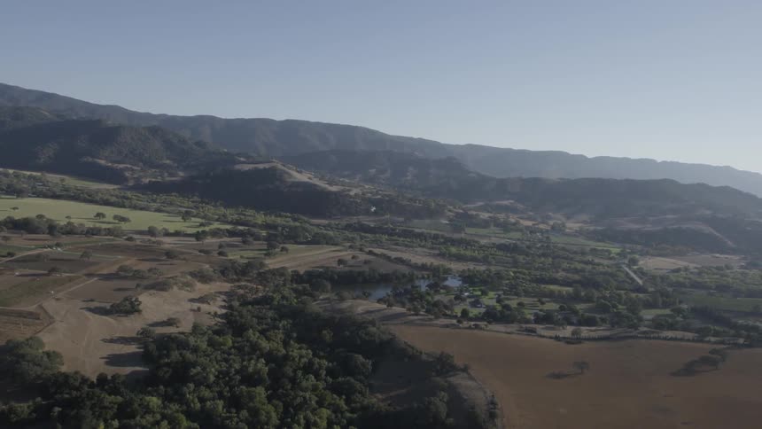 An aerial view of mountains, fields and a small body of water