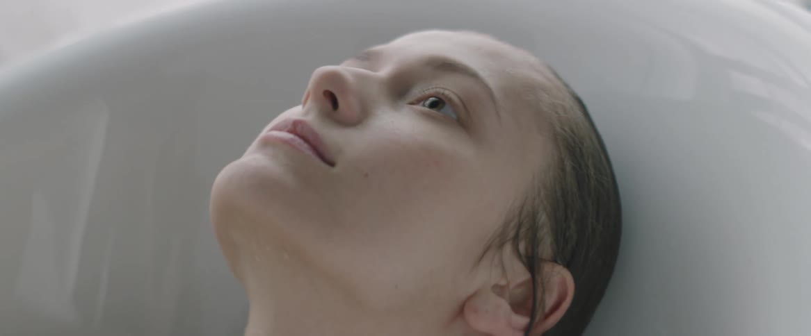 Woman smooths her wet hair as she lays in a bathtub