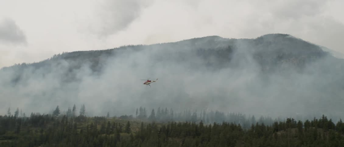 A helicopter flies above a burning fire
