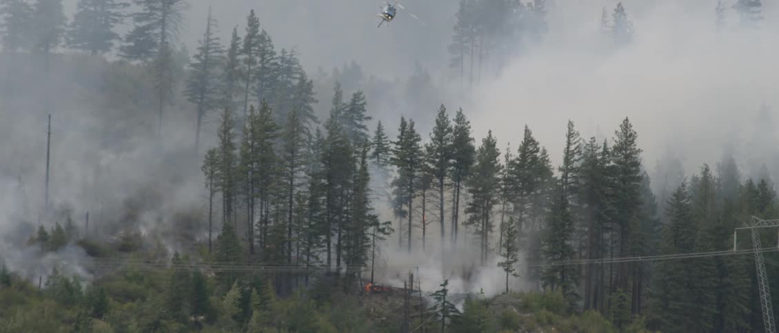 Helicopter sprays water over a burning forest