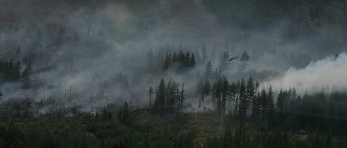 A helicopter dumps water on a wildfire