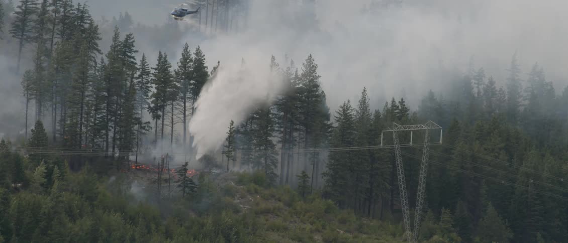 A helicopter dumps water on a forest fire
