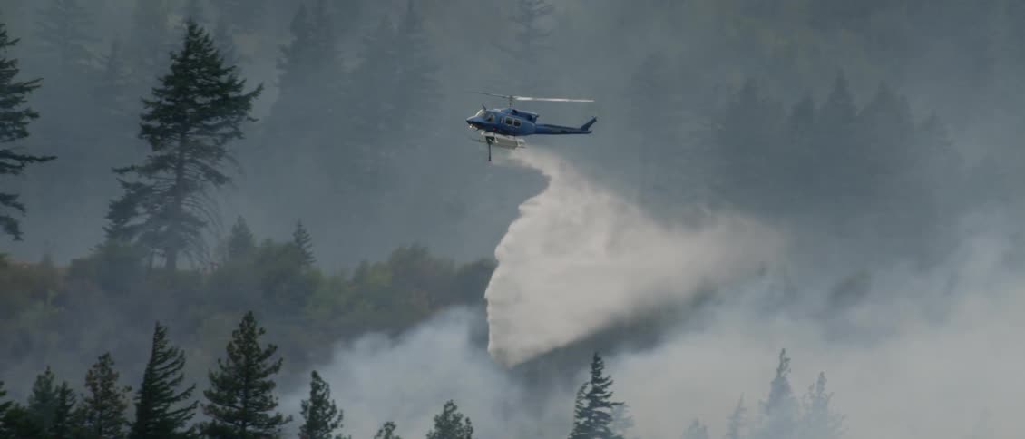 A helicopter dumps water on a wildfire