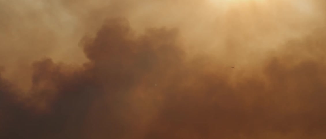 Sunlight shines through dark smoke in the sky
