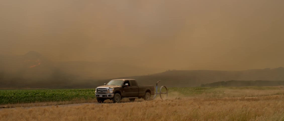 A truck is driving across the green field