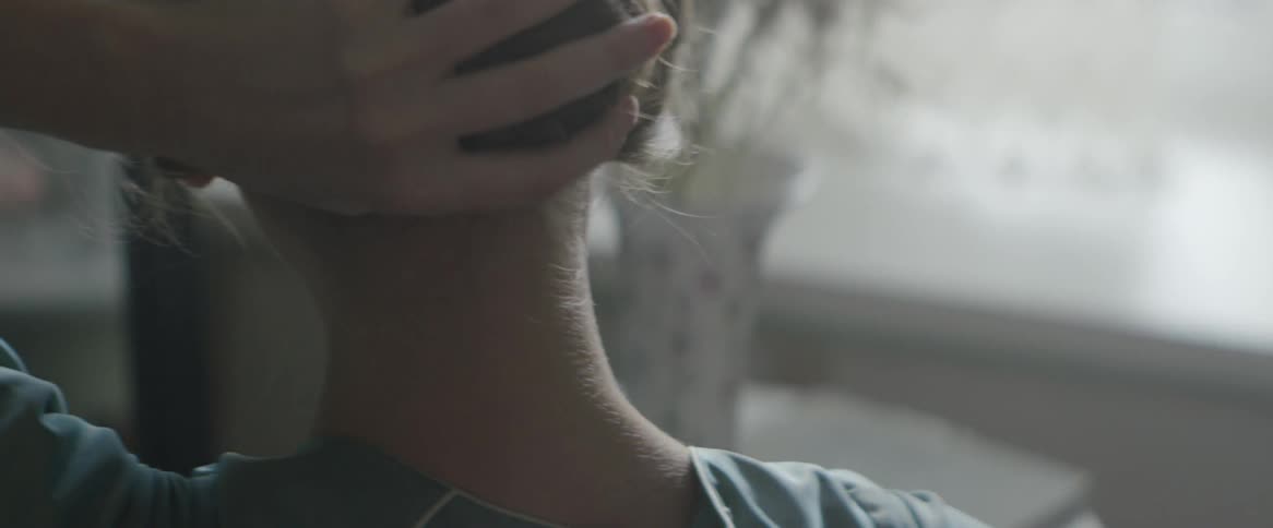 A woman wraps her hair into a bun