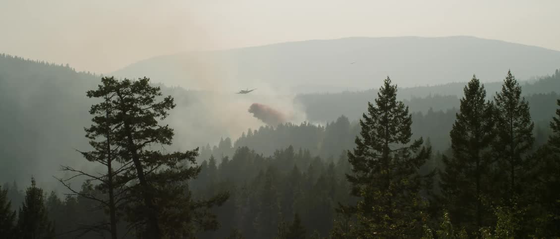 A firefighting plane drops fire retardant on a burning fire