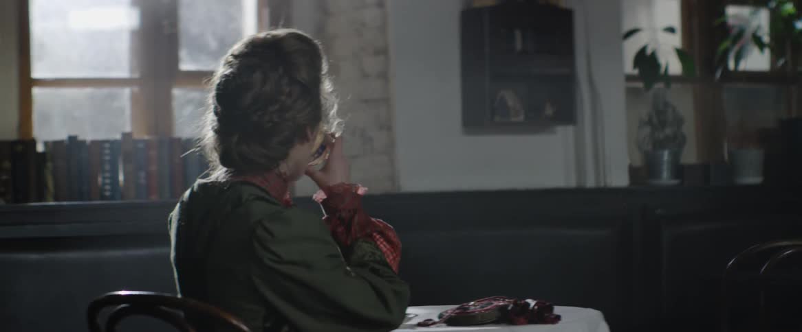 Woman sits at a table and takes a drink out of a tea cup