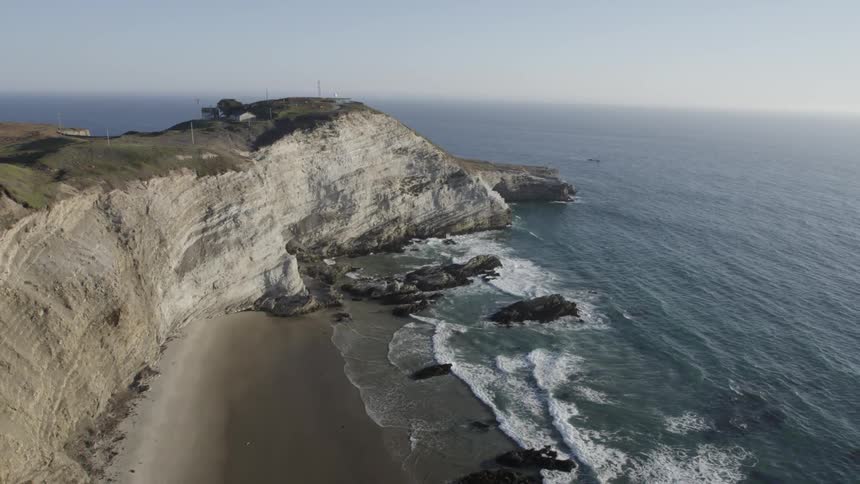 Aerial view of a steep cliff on a coast and wavy sea