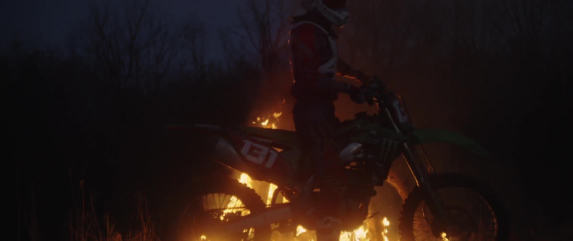 A dirt bike rider approaches a burning fire