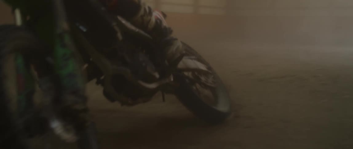 A dirt bike rider drifts and falls down in the dirt