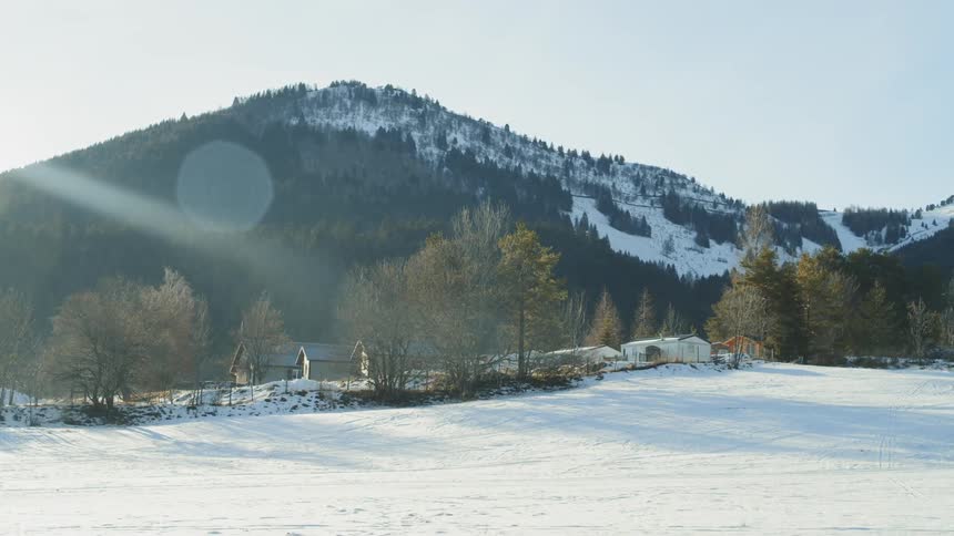Snowy field sits next to a mountain under a blue sky
