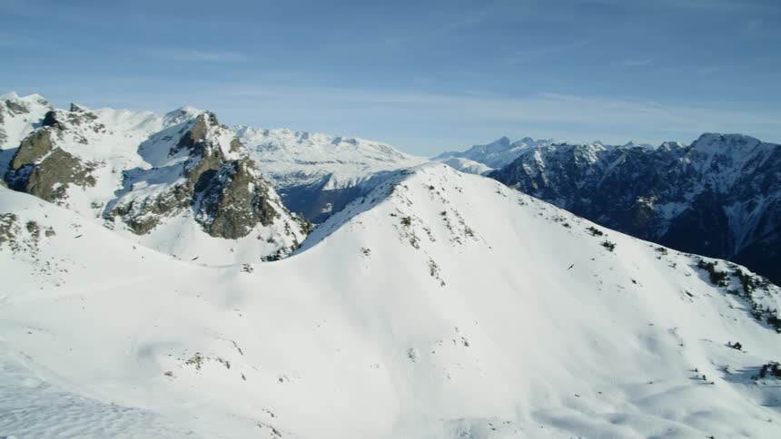 Birds fly over snow covered mountain peaks on a sunny day