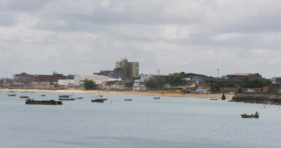 Many boats floating on a large lake next to a city