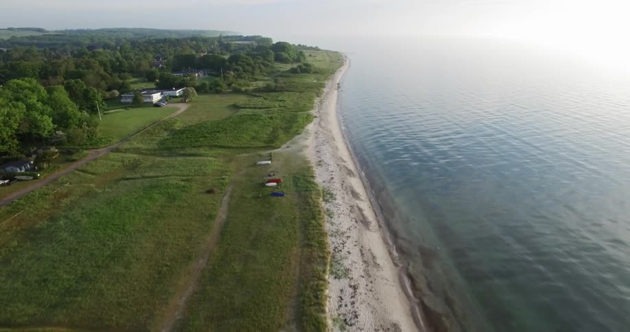 Waves roll into shore next to green fields
