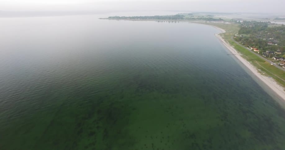Haze in lingering in the air over a coastal community and beach during the day