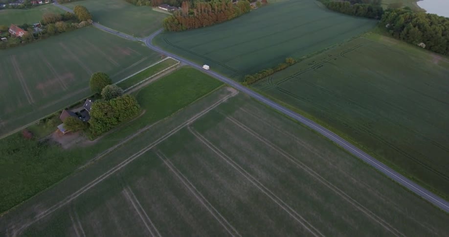 A vehicle travels down a rural farm road