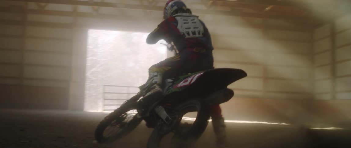 Man spinning out in the dirt on a dirt bike in an enclosed area