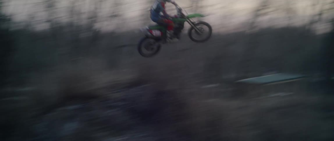 A dirt bike rider performs a jump in the woods