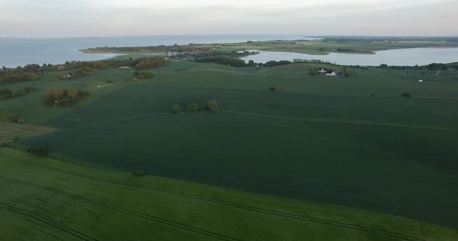 Green fields extend out towards the coastline on a peninsula on a cloudy day